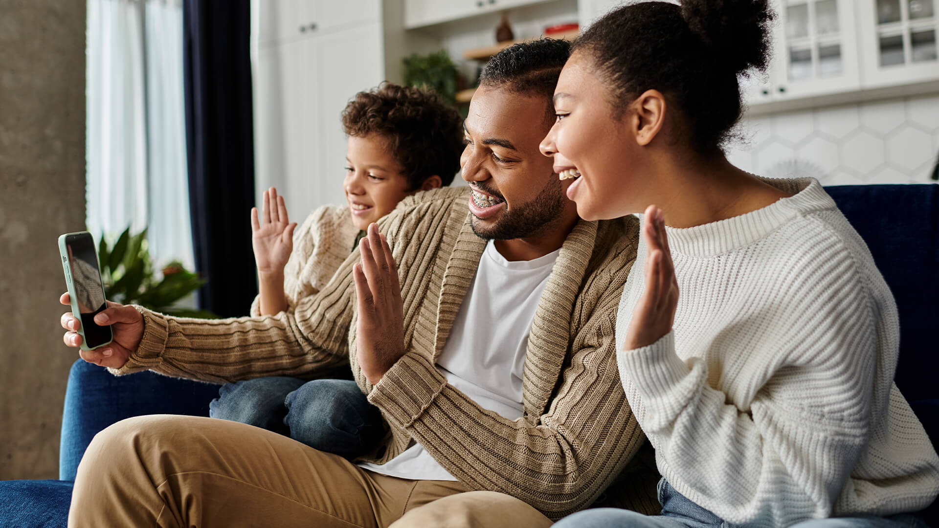 A family waving hello during a video call on a tablet at home